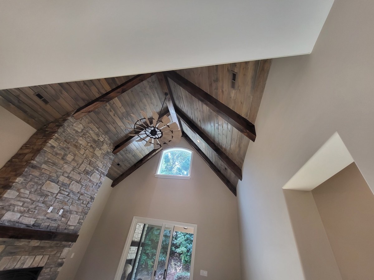 Cathedral ceiling with dark exposed beams over stone fireplace